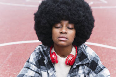 Afro-Frau mit geschlossenen Augen auf dem Sportplatz - PNAF03343