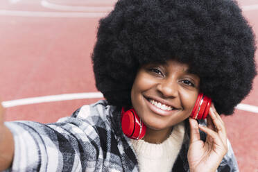 Afro woman listening music on headphones - PNAF03346