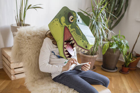 Mädchen mit Dinosauriermaske benutzt Smartphone zu Hause - VGPF00071