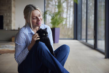 Smiling woman with cat at home - RBF08568