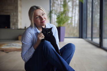 Blond woman with pet cat sitting at home - RBF08569