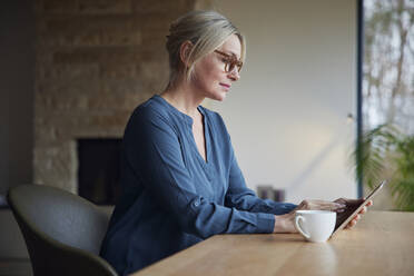 Blonde Frau mit Tablet-PC am Tisch sitzend - RBF08607