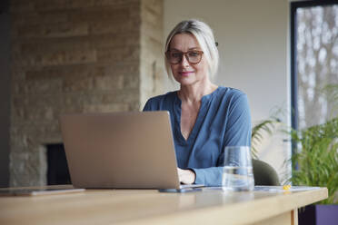 Blonde Frau mit Laptop am Tisch sitzend - RBF08609