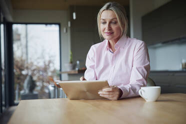 Woman using tablet PC sitting at table - RBF08612