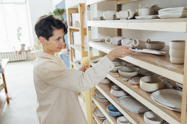Owner examining ceramics at workshop - VPIF05548