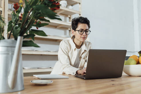 Craftswoman with eyeglasses using laptop at workshop - VPIF05555