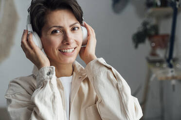 Lächelnde Frau hört Musik über Kopfhörer - VPIF05591