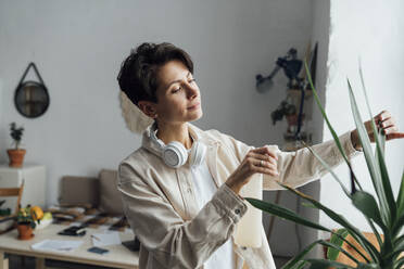 Woman spraying water on plants at workshop - VPIF05595