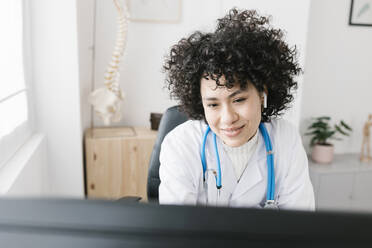 Ärztin mit lockigem Haar bei der Arbeit in einer medizinischen Klinik - XLGF02753