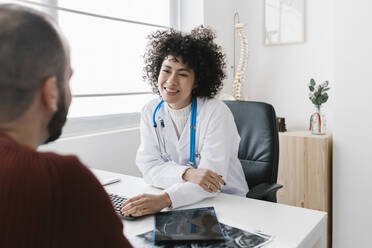 Young doctor talking with patient at medical clinic - XLGF02765