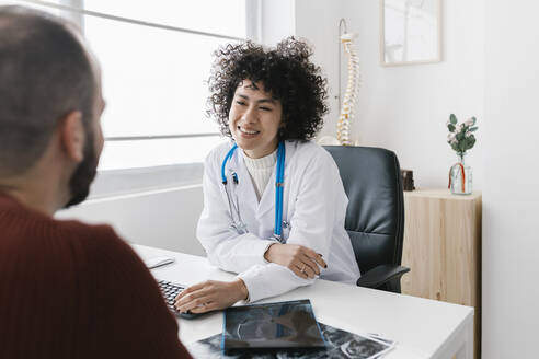 Junger Arzt im Gespräch mit einem Patienten in einer medizinischen Klinik - XLGF02765