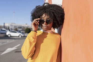 Young woman wearing sunglasses leaning on wall - JCCMF05477