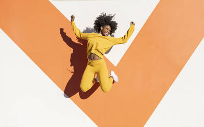 Lächelnde junge Frau springt an einem sonnigen Tag - JCCMF05481