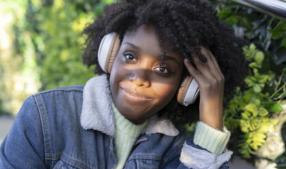 Lächelnde Frau hört Musik über drahtlose Kopfhörer - JCCMF05491