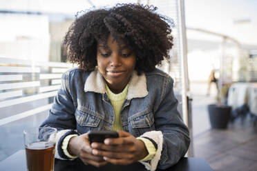 Junge Frau mit Mobiltelefon im Café sitzend - JCCMF05492