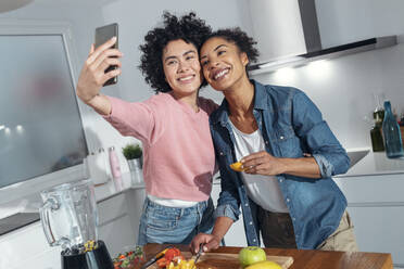 Glückliche Freunde, die ein Selfie machen, obwohl sie in der Küche zu Hause stehen - JSRF01906