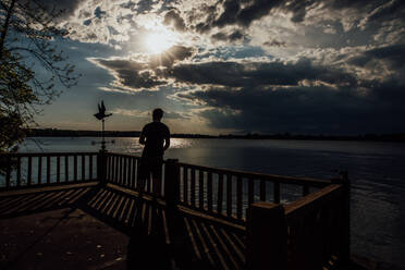 Mann an Deck bei Sonnenuntergang über dem See und denkt nach - CAVF95367