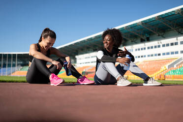 Optimistic female athletes talking during break - CAVF95419