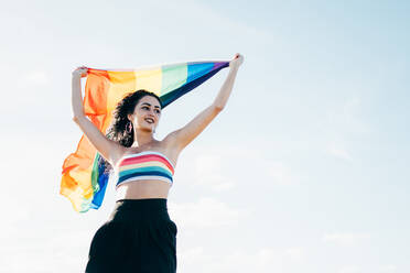 Smiling woman holding LGBT rainbow flag - CAVF95452