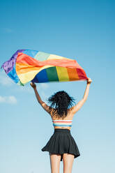 Woman on her back with open arms waving an lgbt flag - CAVF95453