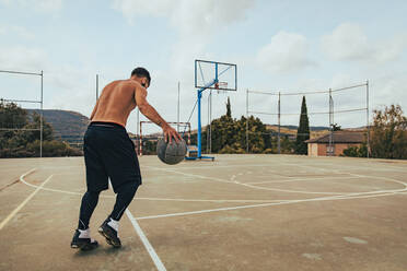 Young boy training alone on a basketball court - CAVF95464