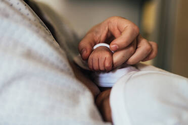 Die Hand der Mutter hält die Hand ihres neugeborenen Babys beim Stillen. - CAVF95489