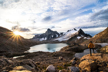 Junger Mann mit Blick auf den Sonnenaufgang im Hochgebirge der Selkirks - CAVF95497