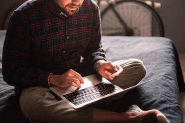 Man using credit card and laptop computer shopping online at home - CAVF95526