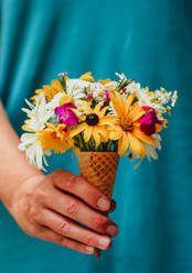 Nahaufnahme einer Hand, die eine Zuckertüte voller Wildblumen hält. - CAVF95534