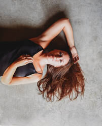 Overhead view of beautiful brunette woman laying on concrete floor. - CAVF95558