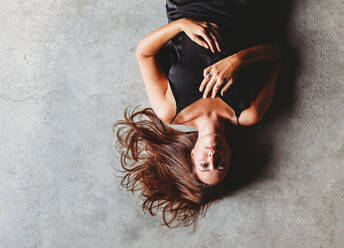 Overhead view of beautiful brunette woman laying on concrete floor. - CAVF95559