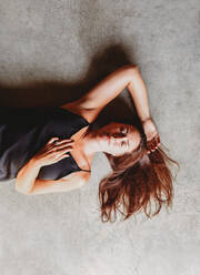 Overhead view of beautiful brunette woman laying on concrete floor. - CAVF95560