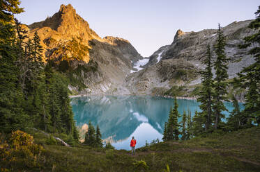 Female In Red Jacket Next To Gorgeous Blue Alpine Lake At Sunset - CAVF95634