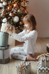Das Mädchen macht Schachteln mit Geschenken übereinander - CAVF95655