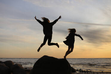 Silhouetten von springenden Kindern auf dem Hintergrund des Sonnenuntergangs. - CAVF95660