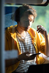 Young man, teenager in headphones , traveling in train, listen music. - CAVF95677