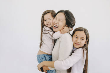 Niedliche Töchter umarmen glückliche Mutter durch weißen Hintergrund - ORF00019