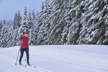 Ältere Frau beim Skifahren im Winterwald - MRF02508