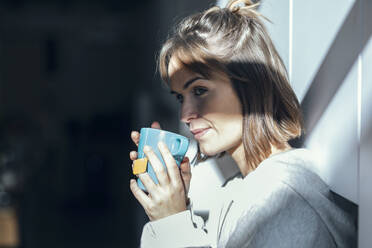 Frau trinkt Kaffee an der Wand - JSRF01922