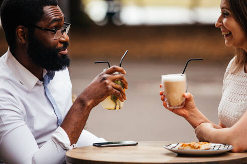 Das glückliche Paar trinkt und hat Spaß in einem Straßencafé - CAVF95706