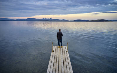 Mann steht auf Pier in der Nähe von See - CAVF95712