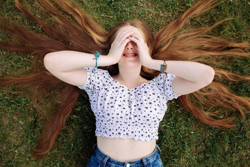 Young ginger teen girl smiling and covering her eyes with hands - CAVF95717