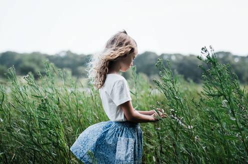 Mädchen, das durch Blumen geht und sich den Wind um die Haare wehen lässt - CAVF95723