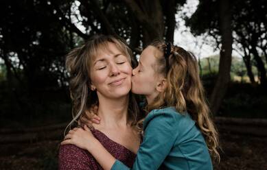 Tochter küsst Mutter auf die Wange, während sie im Freien ist - CAVF95727