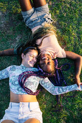 Multirassisches weibliches Paar, das im Gras liegt. Lesbisches Paar - CAVF95735
