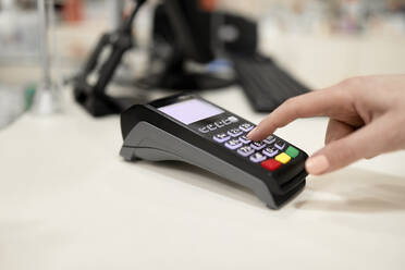 Hand mit Kreditkartenlesegerät an der Kasse im Geschäft - ZEDF04443