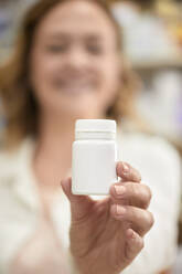 Pharmacist with bottle of medicine at pharmacy - ZEDF04449