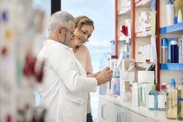 Pharmacist assisting customer with medicine at pharmacy store - ZEDF04472