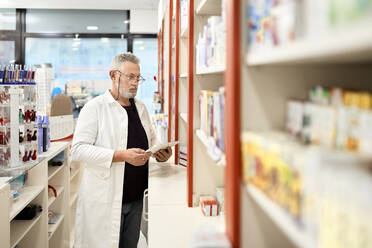 Pharmacist holding tablet PC working in pharmacy store - ZEDF04481