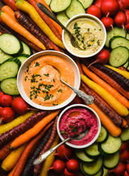 Bowls of different flavoured hummus and raw vegetables for dipping. - CAVF95802